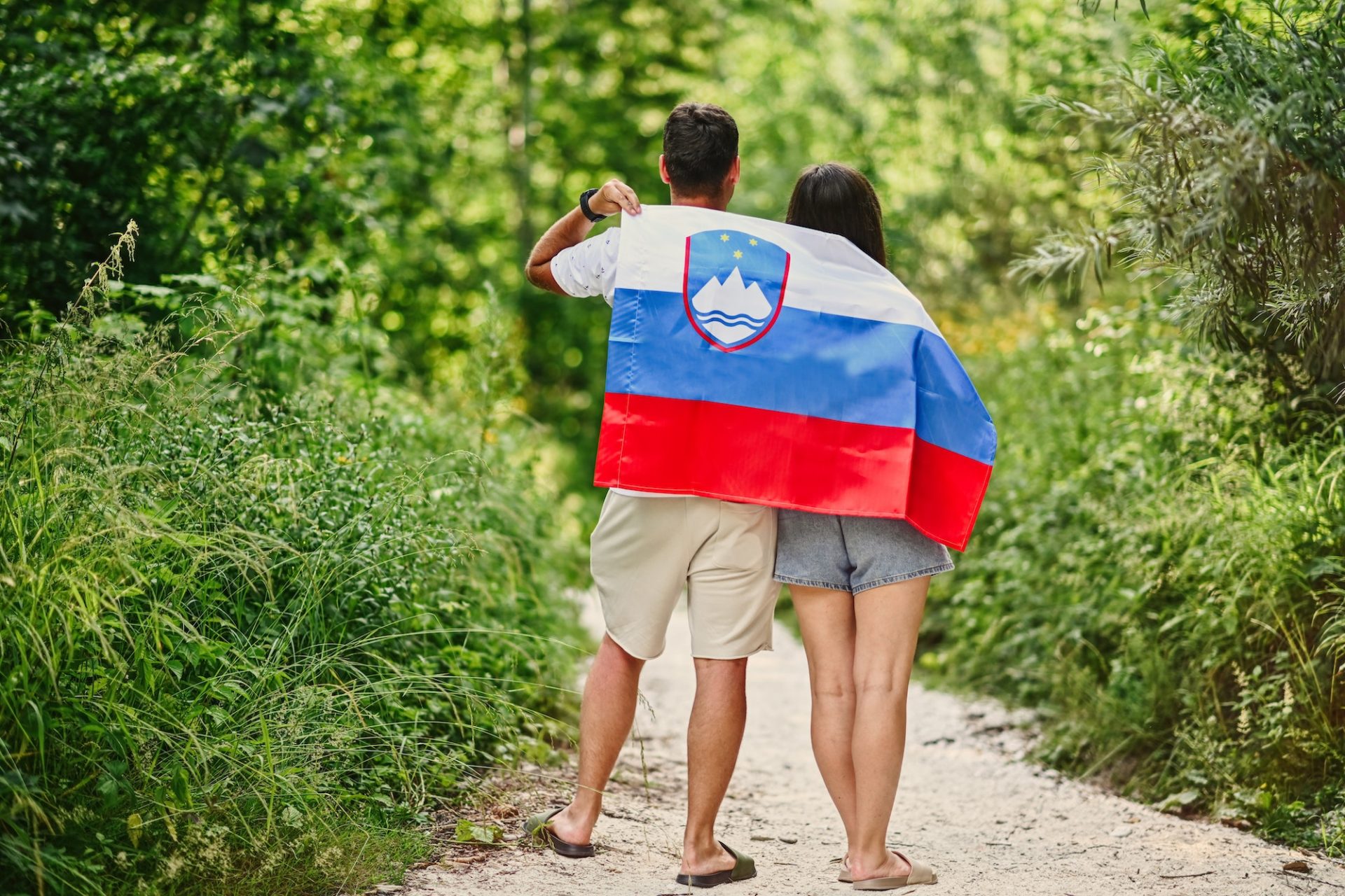 Back of couple hold slovenian flag in Triglav National Park, Slovenia.