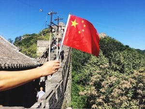 Hand holding flag of China in the Great Wall of China