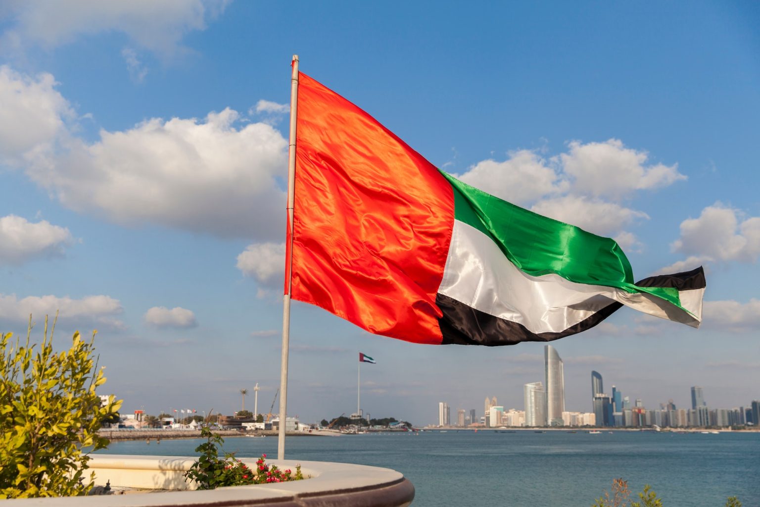 UAE flag with Abu Dhabi cityscape at the background, patriotism, flag day, national day